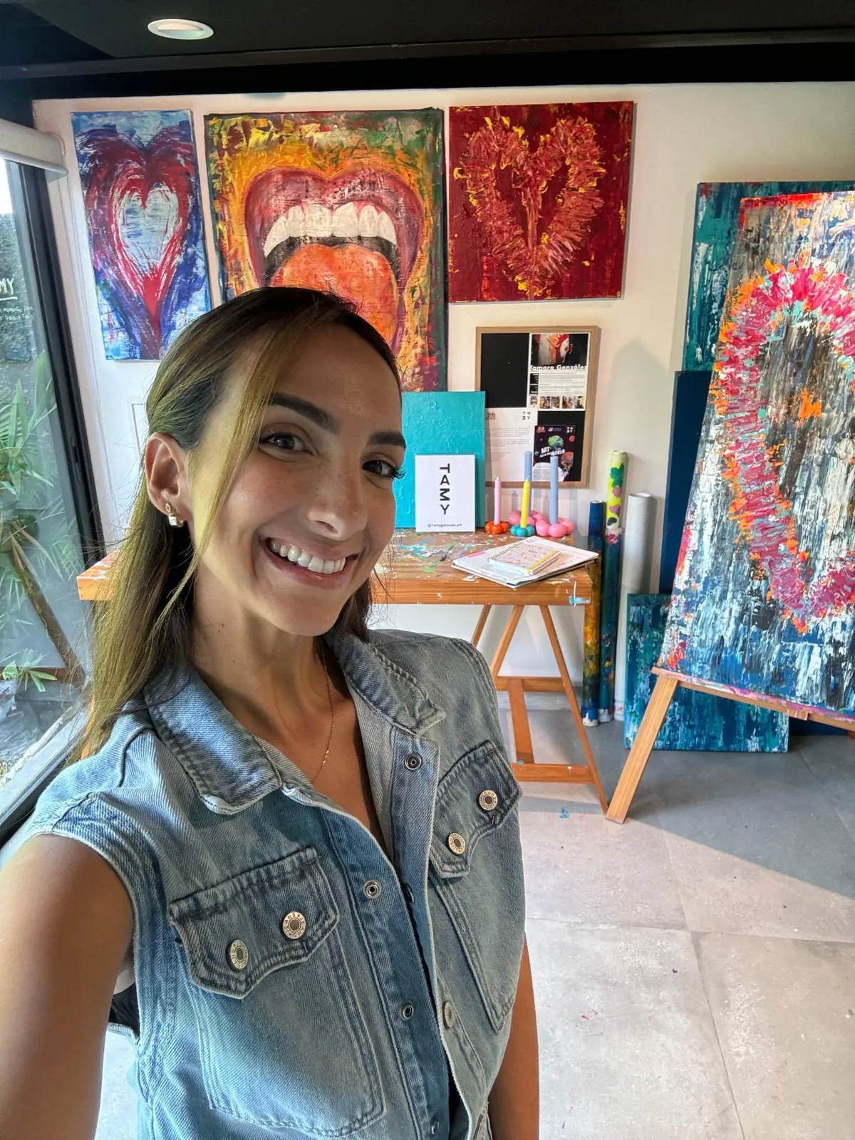 Tamy en su estudio, con sus obras al fondo